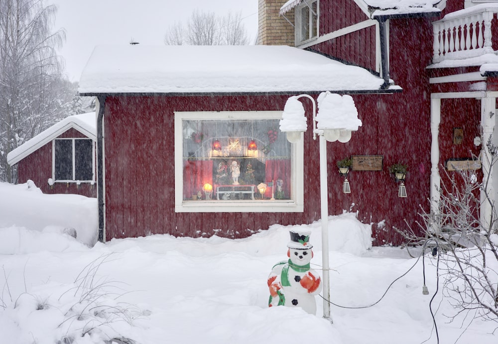 a snowman in front of a red house