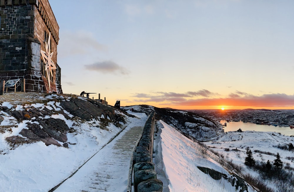 the sun is setting over a snow covered hill