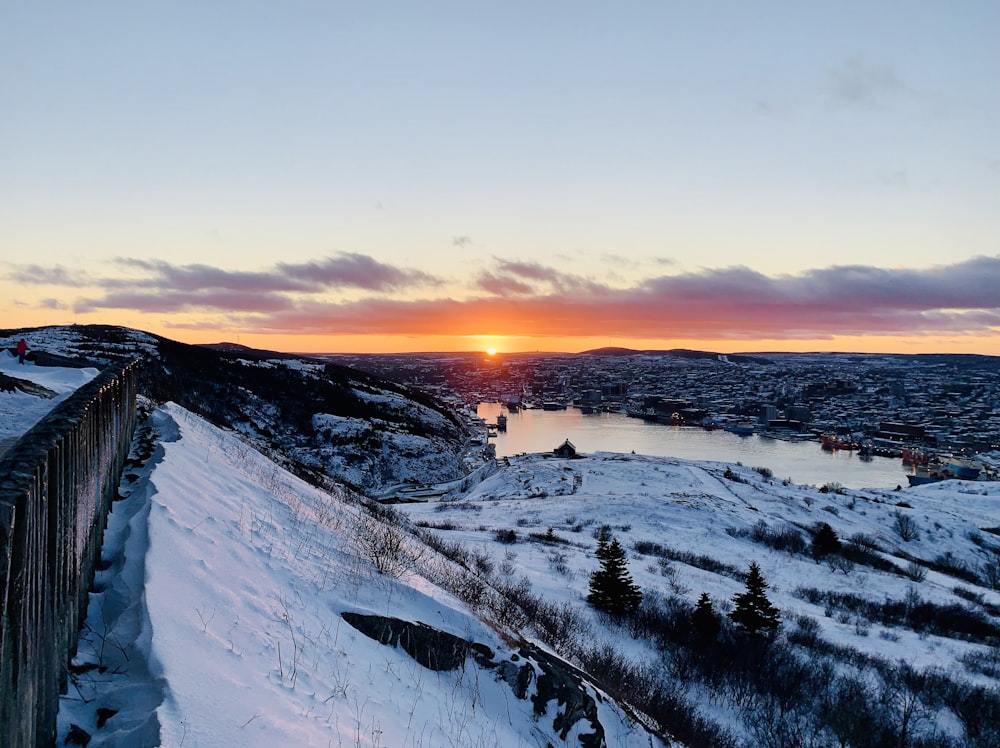 the sun is setting over a snowy landscape