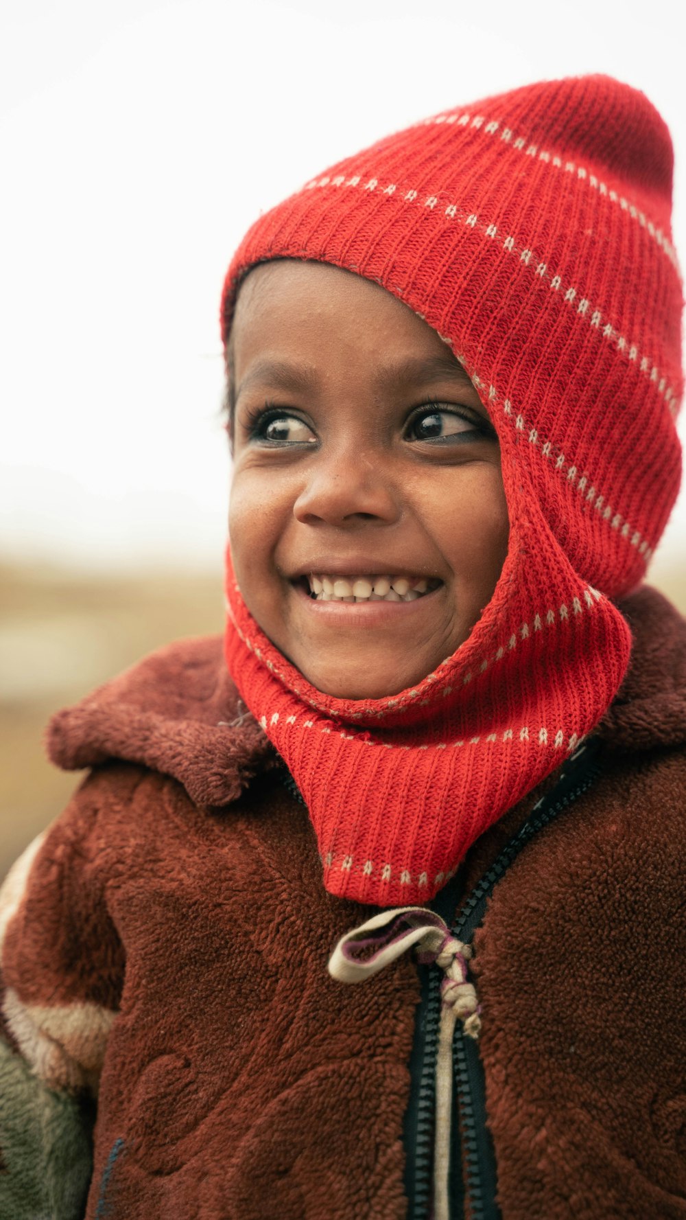 a young boy wearing a red hat and scarf