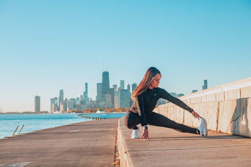 a woman stretching her legs on a pier