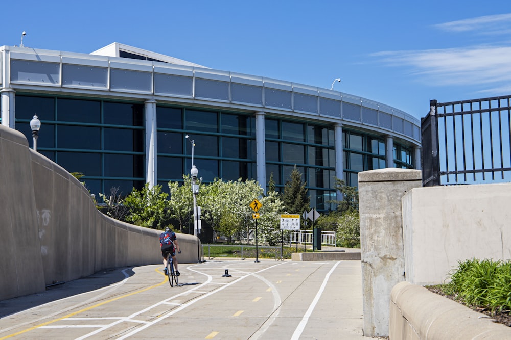 a man riding a bike down a street next to a tall building