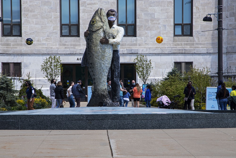 a statue of a man holding a fish in front of a building