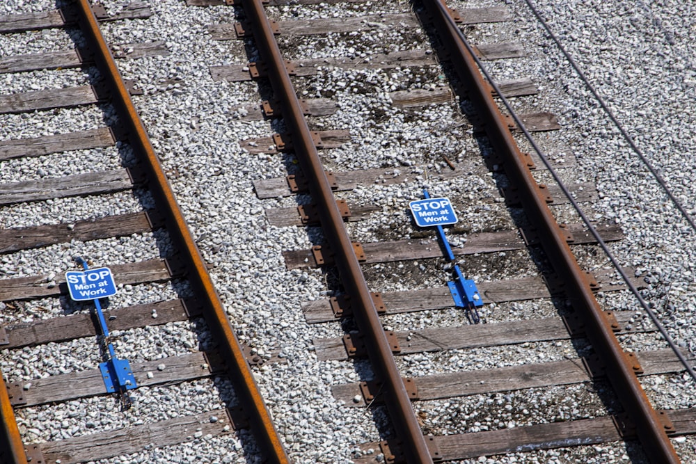 two blue street signs sitting on top of train tracks