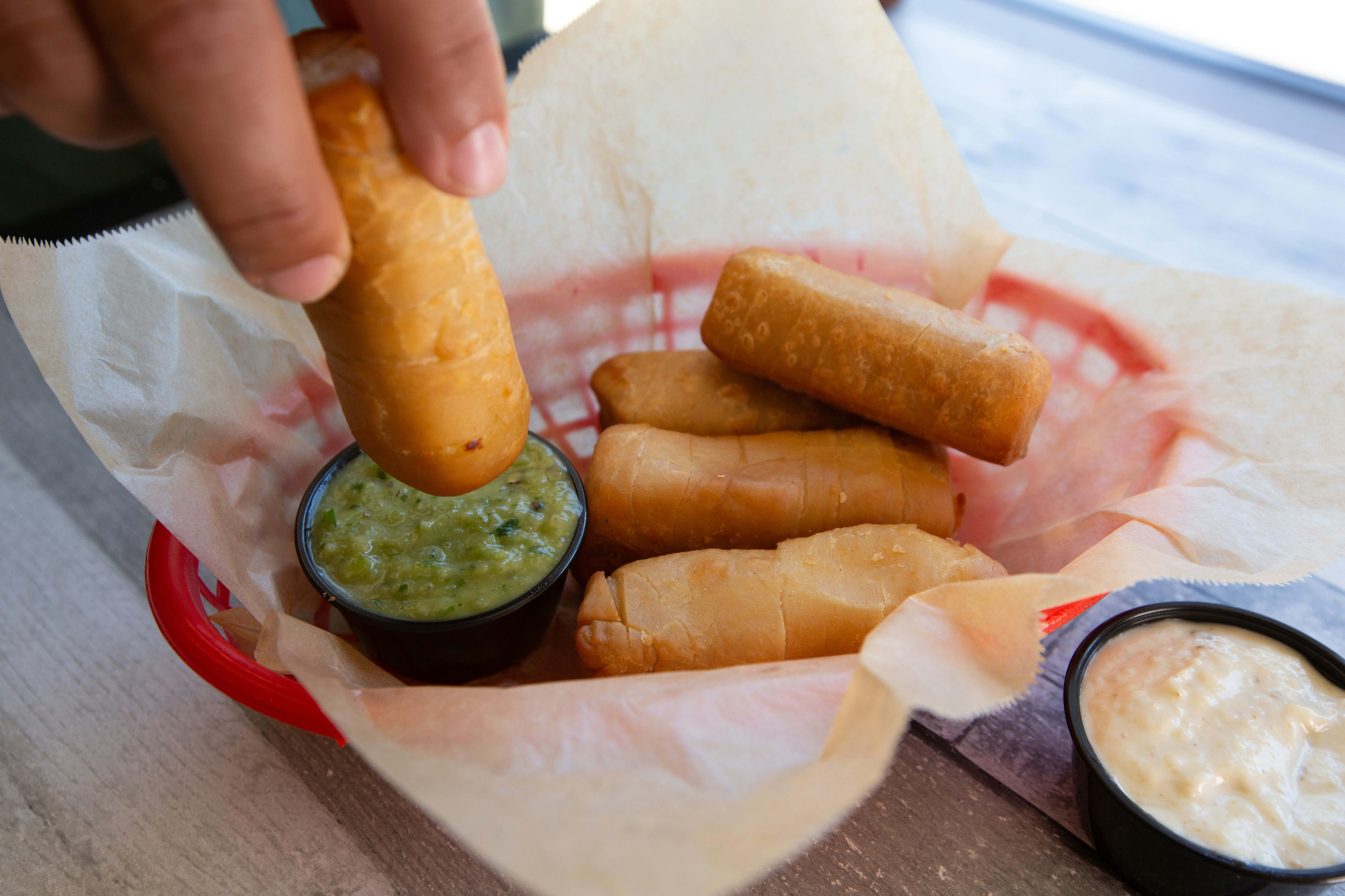 a person dipping a piece of food into a basket