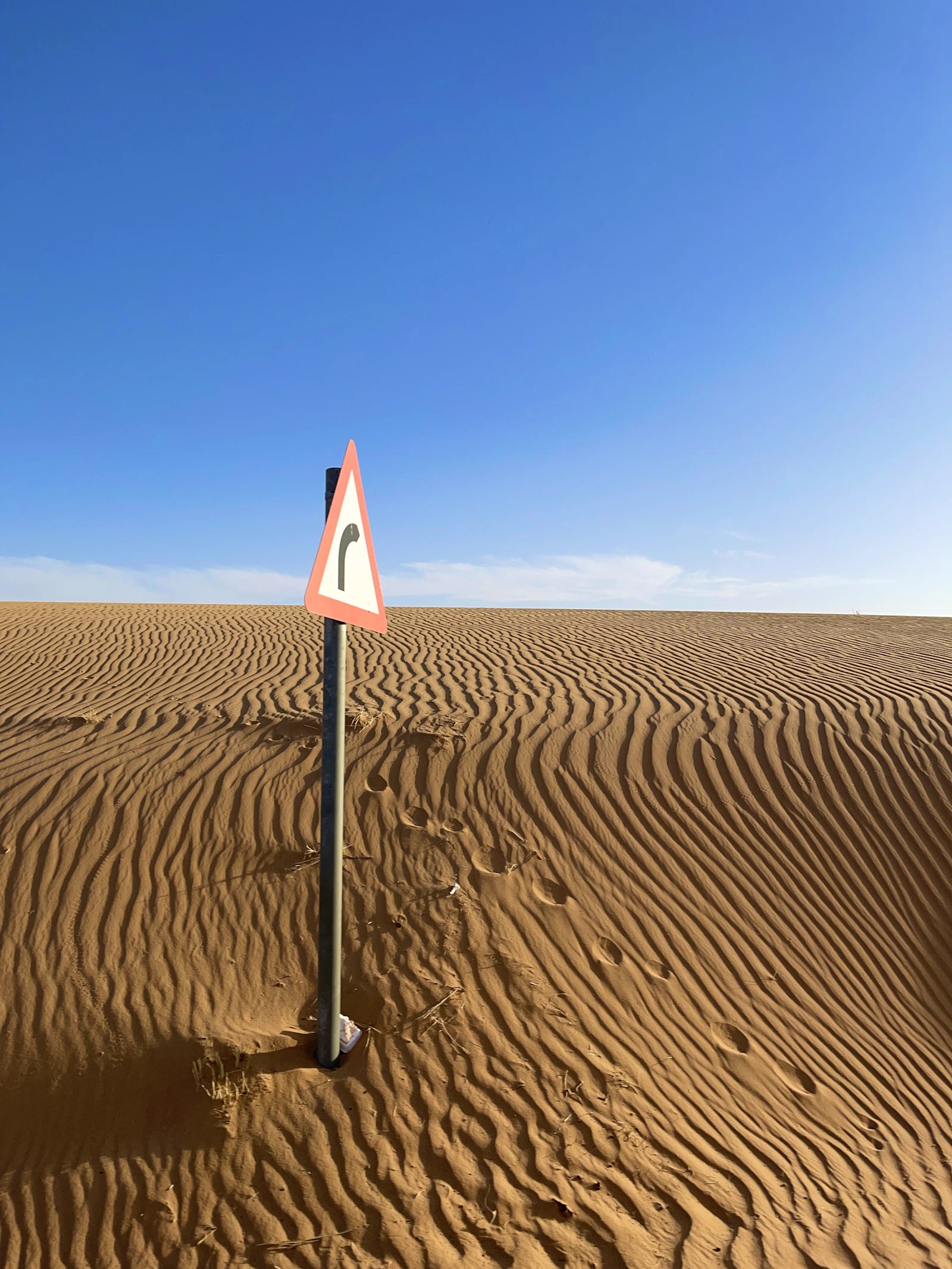 A bend warning sign beside the Nafud desert in Saudi Arabia