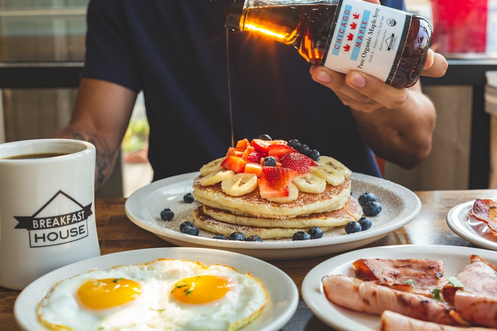 a man is pouring syrup on a stack of pancakes