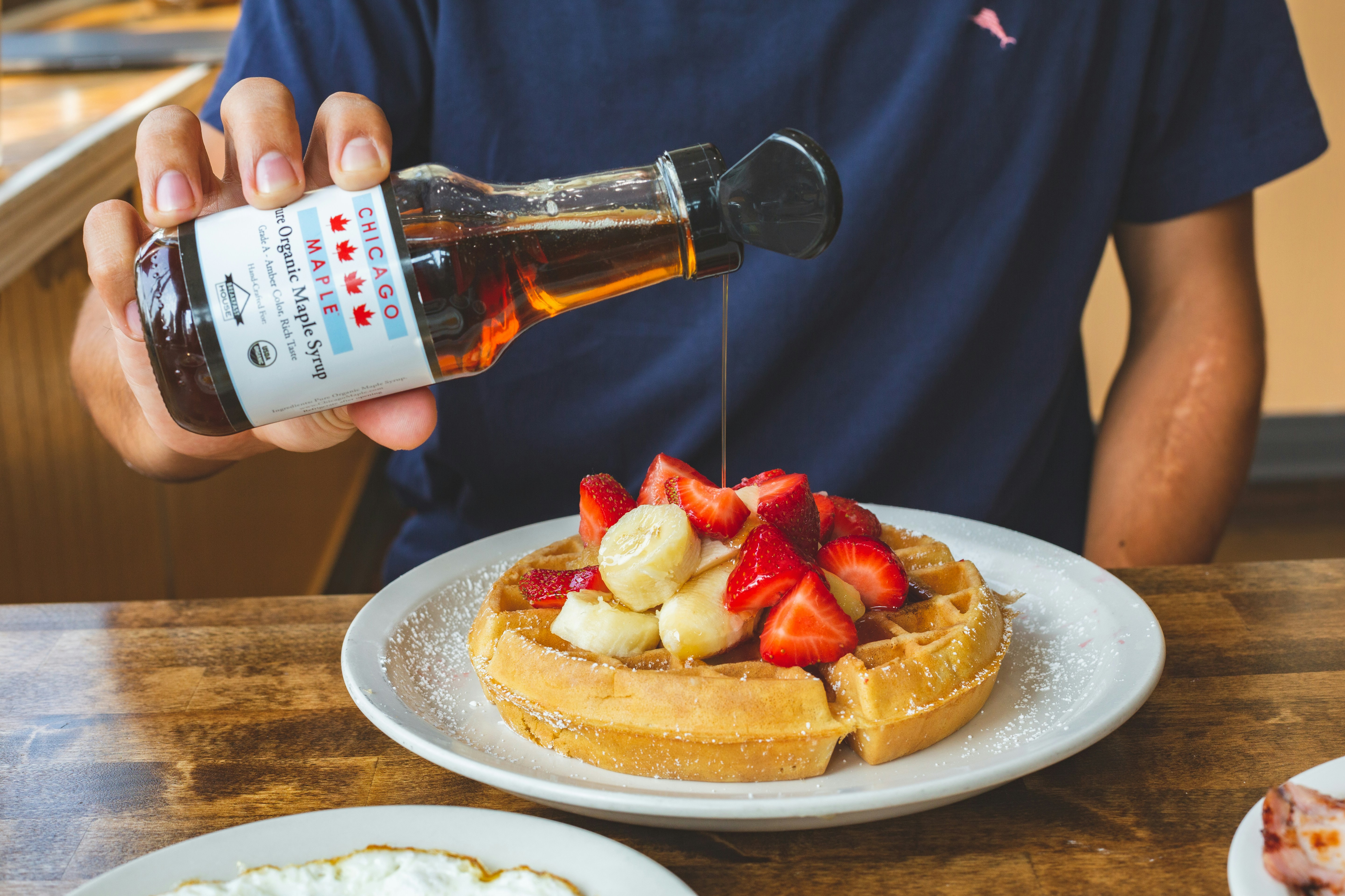 a person pouring syrup on a plate of waffles