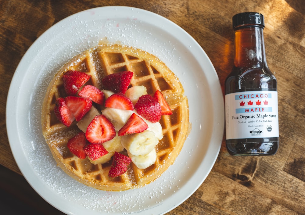 a white plate topped with waffles covered in fruit