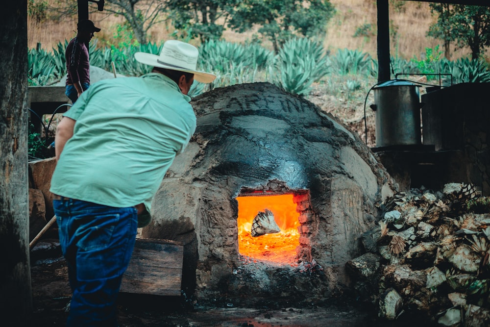 a man standing in front of a stone oven