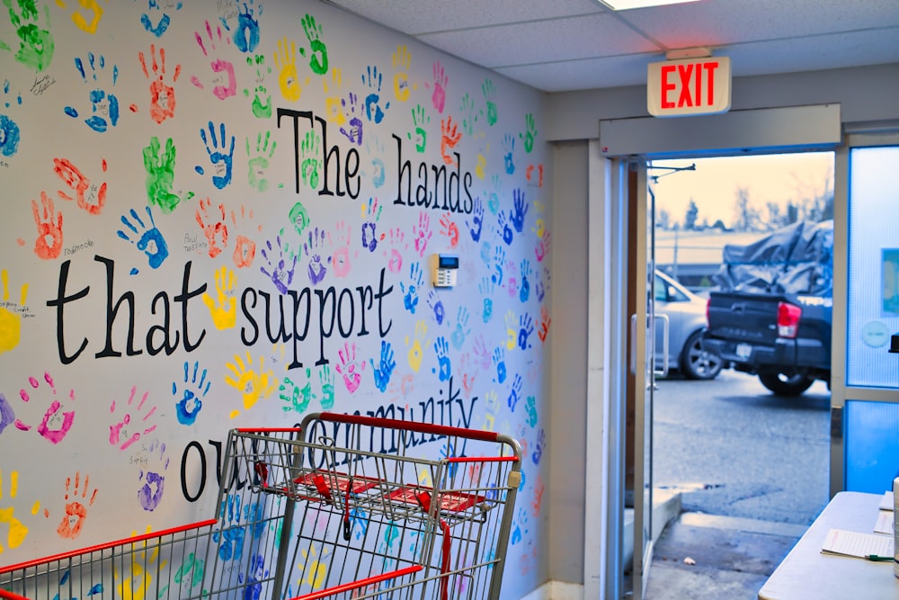 a shopping cart sitting in front of a wall with handprints on it