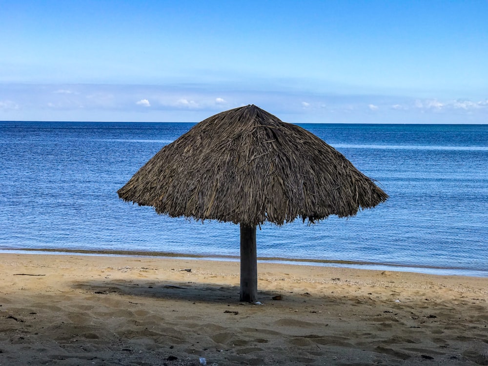 a straw umbrella on a beach next to the ocean