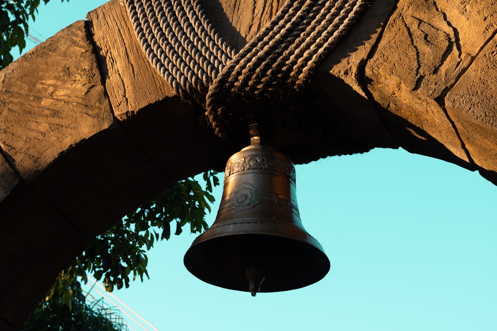 a bell hanging from a wooden structure next to a tree
