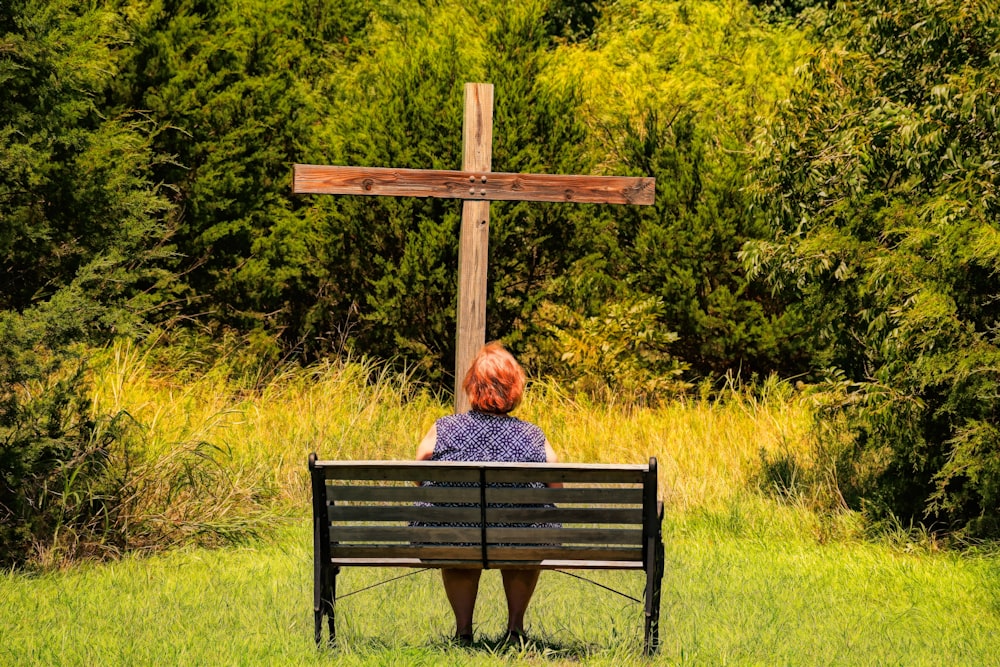 a woman sitting on a bench in front of a cross