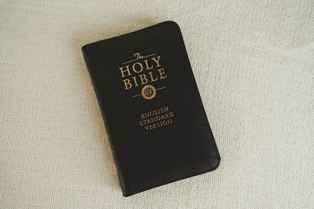 a black bible laying on top of a white blanket