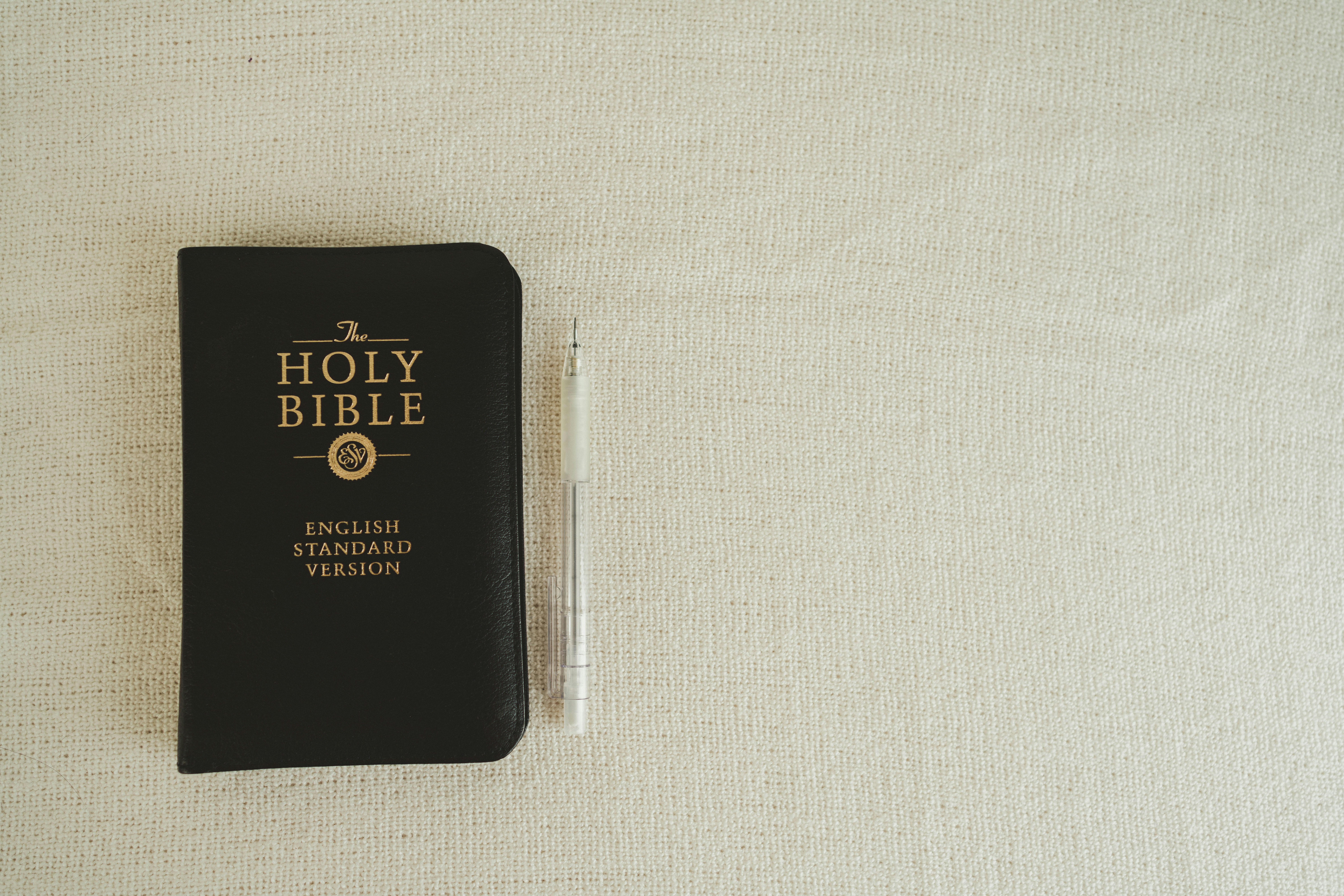 a black bible with a pen on top of it