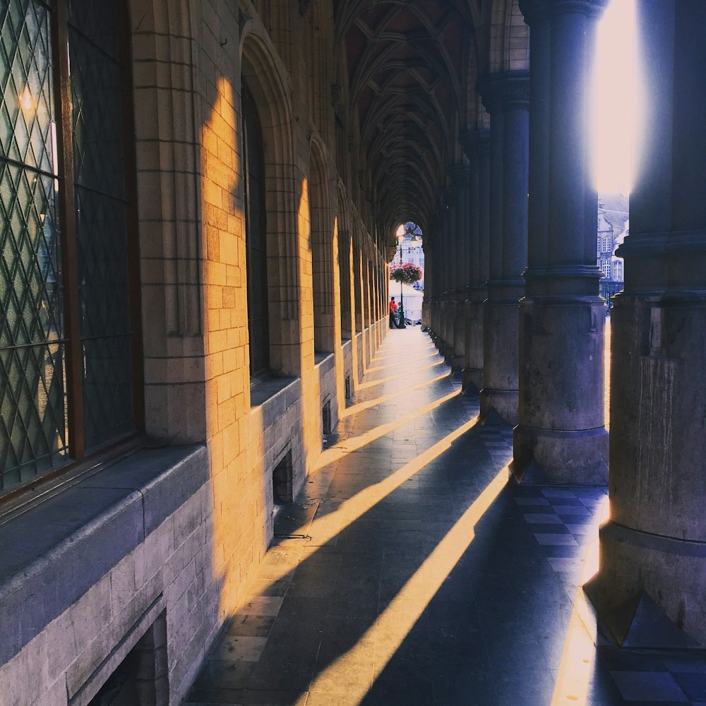 a long hallway with columns and a clock tower in the background