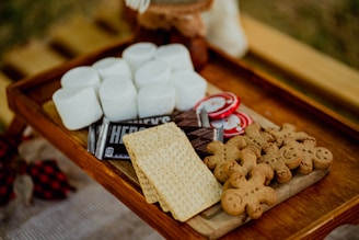 a wooden tray topped with marshmallows and crackers