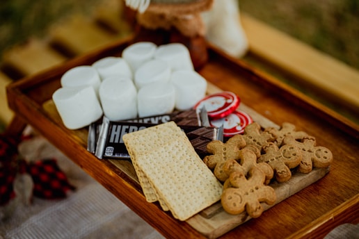 a wooden tray topped with marshmallows and crackers