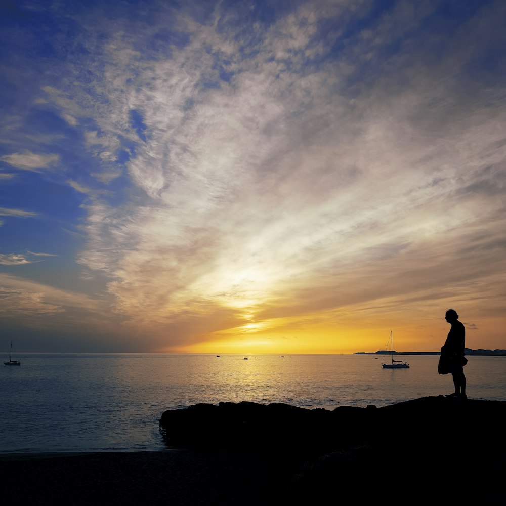 a person standing on a rock looking out at the water