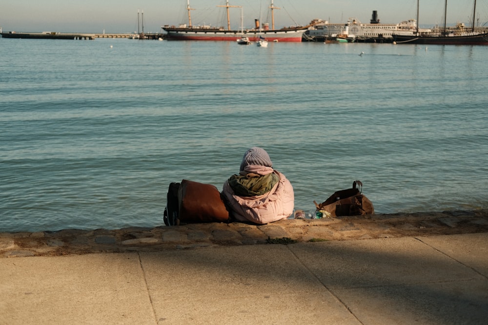 a woman sitting on a wall next to a body of water
