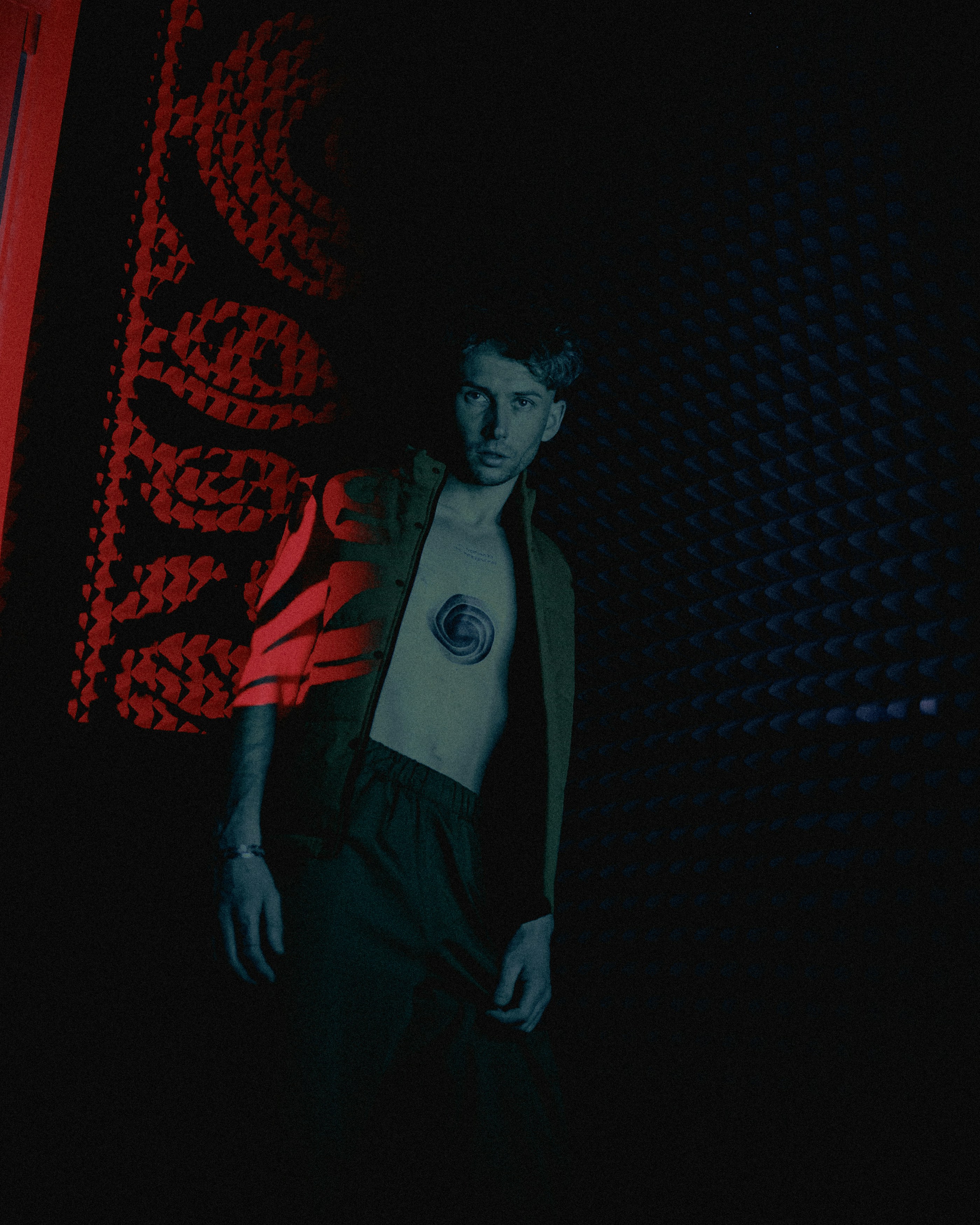 a man standing in front of a red and black wall