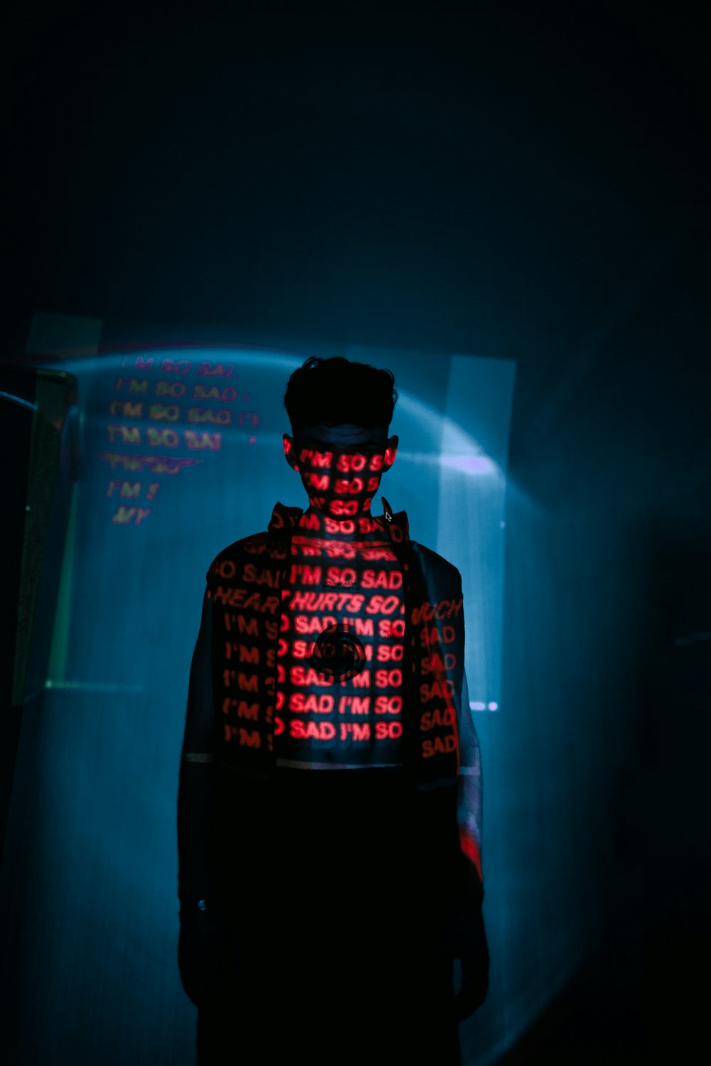 Un homme debout dans une pièce sombre avec une lumière rouge sur le dos