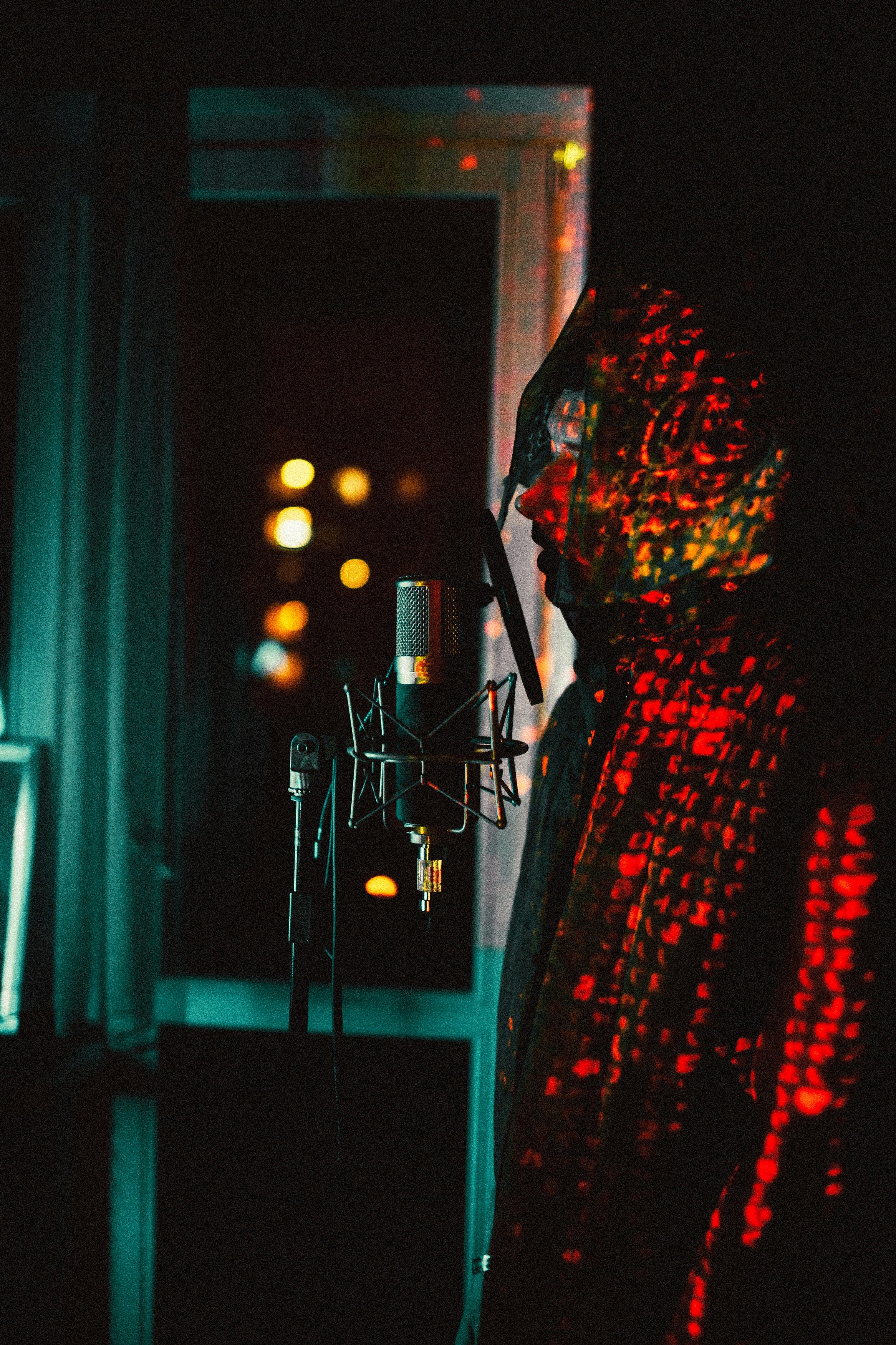 a woman standing in front of a microphone in a dark room