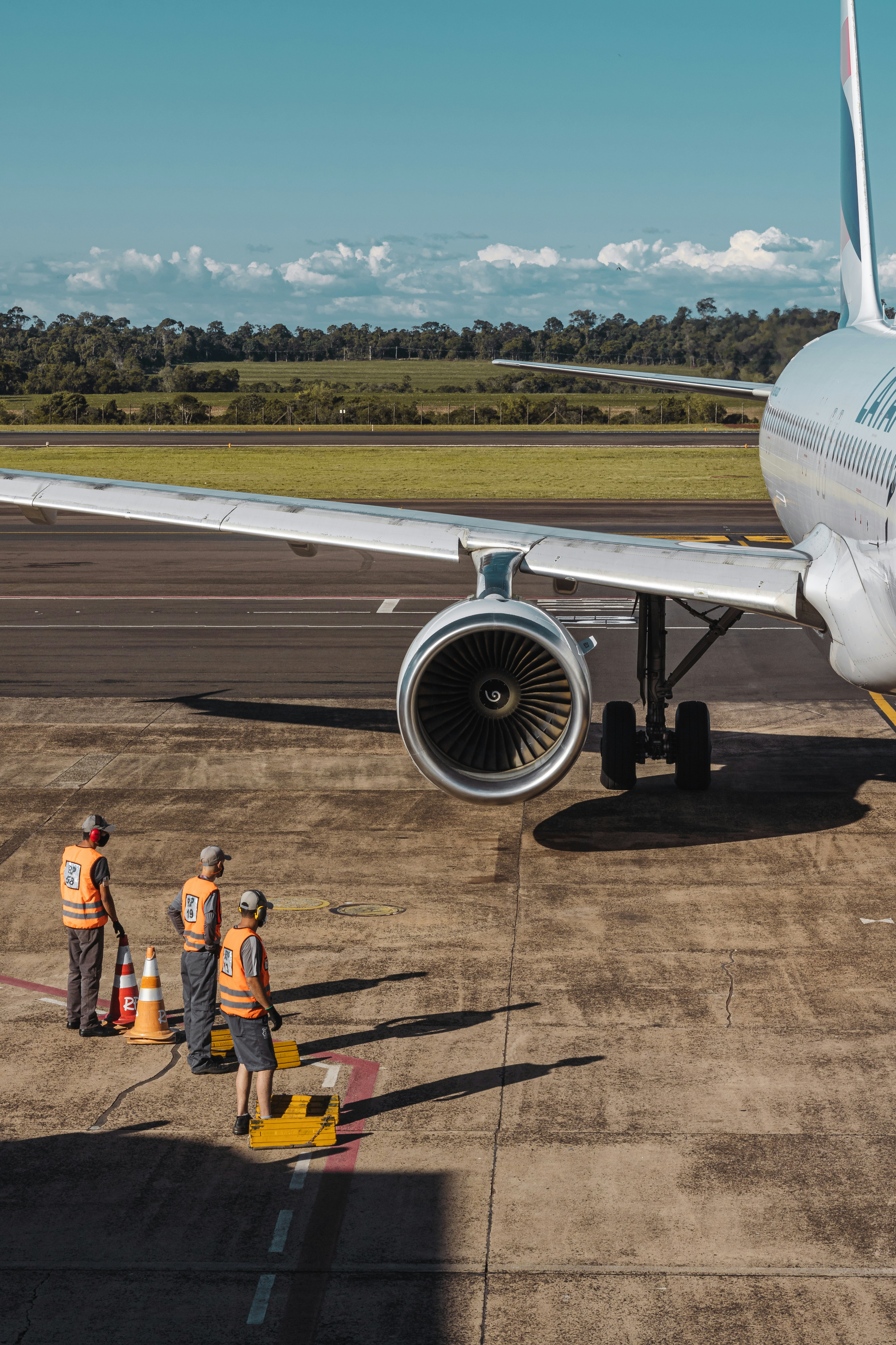 Ground crew members stand near a large airplane on the tarmac.