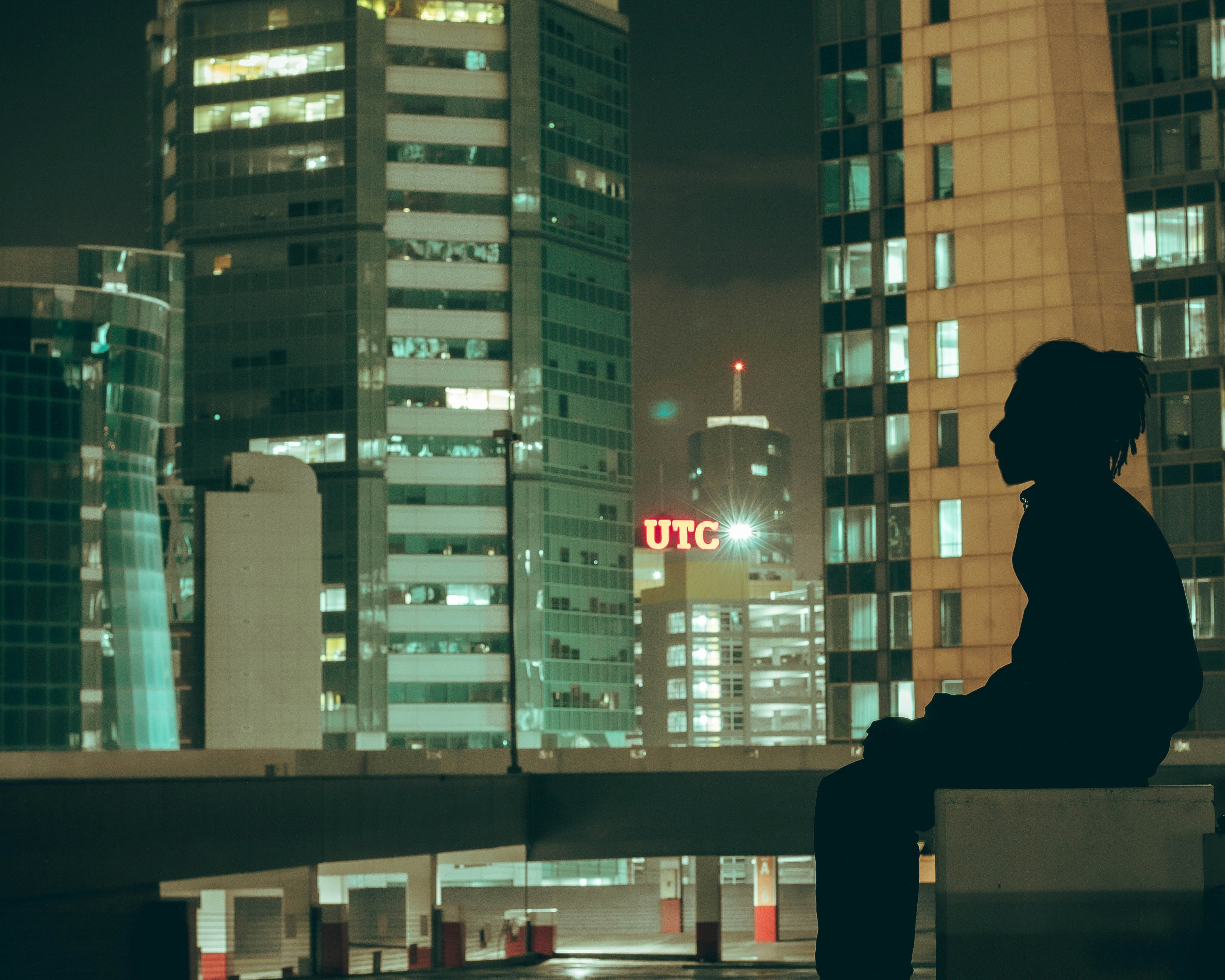 Young woman feeling alone in the city on a rooftop at night