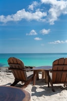 a couple of chairs sitting on top of a sandy beach