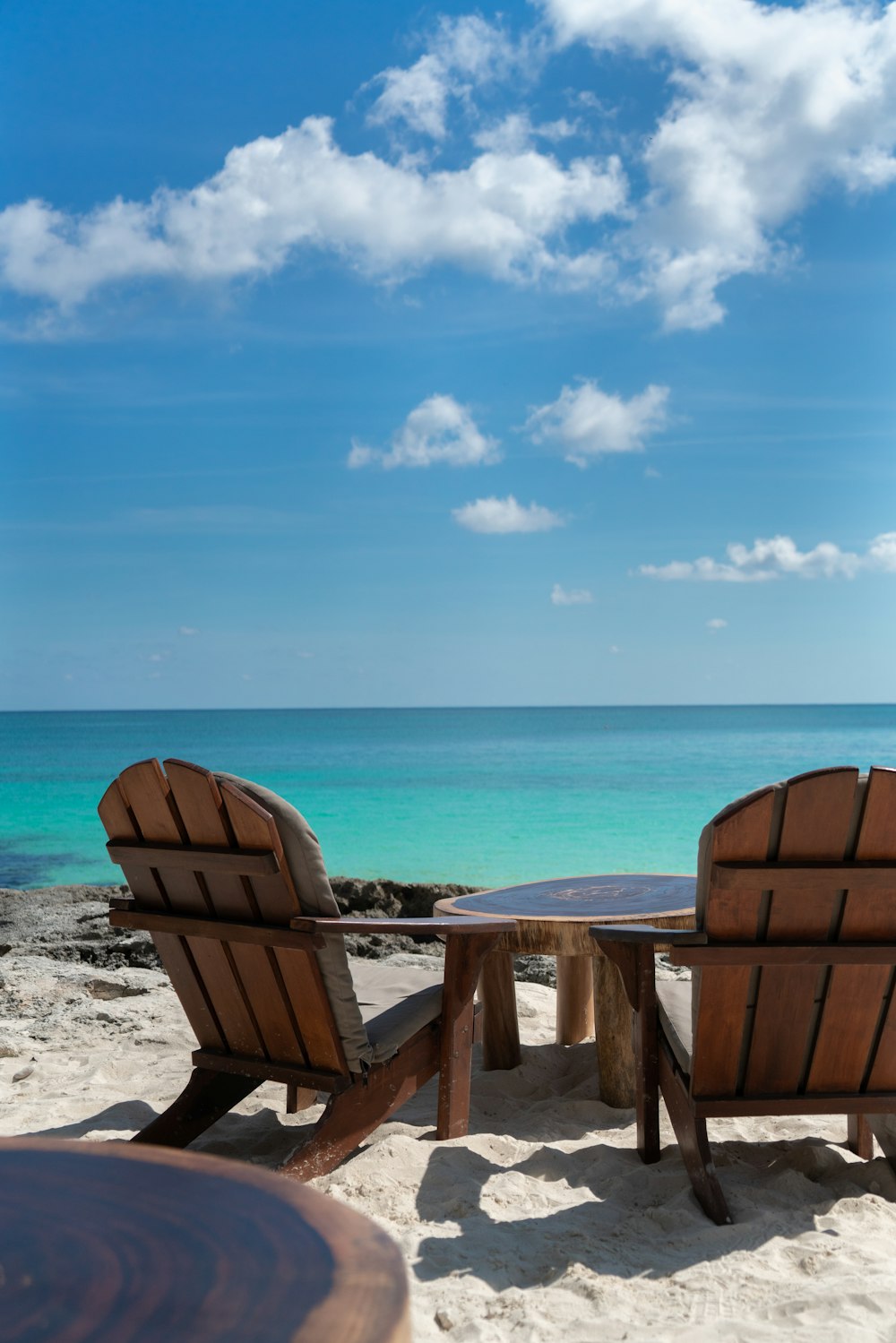 a couple of chairs sitting on top of a sandy beach