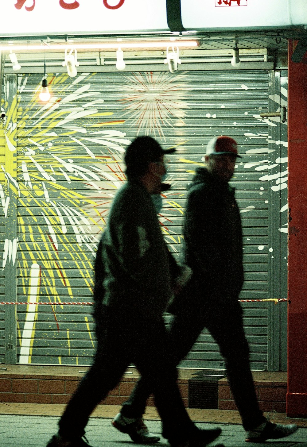 a couple of men walking down a street next to a building