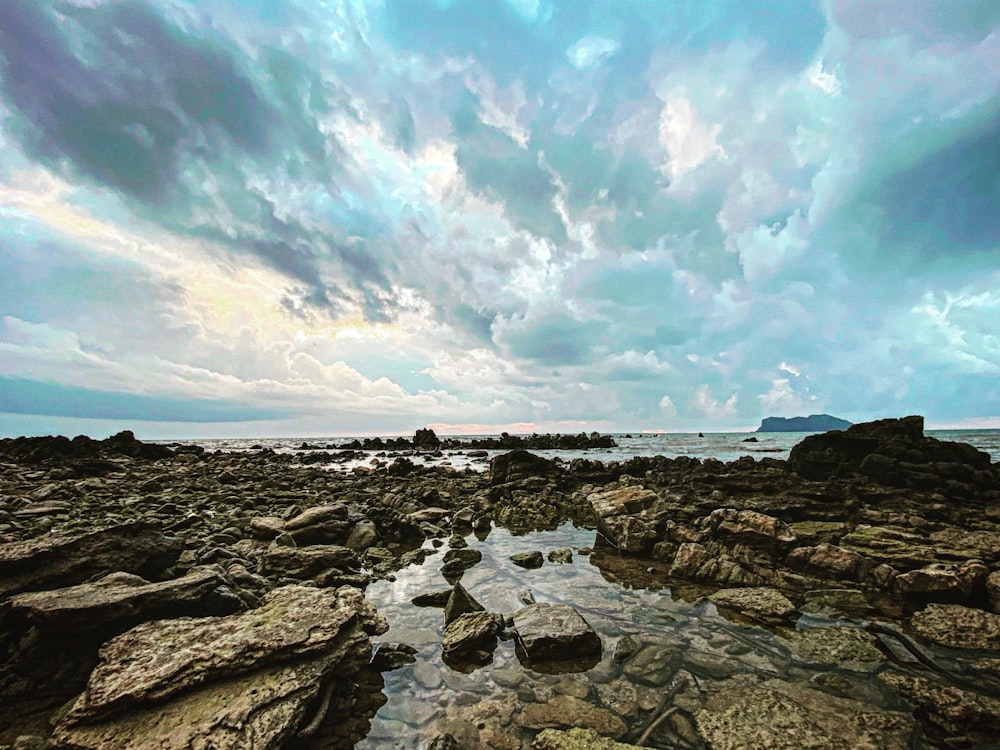 a rocky beach covered in lots of rocks under a cloudy sky