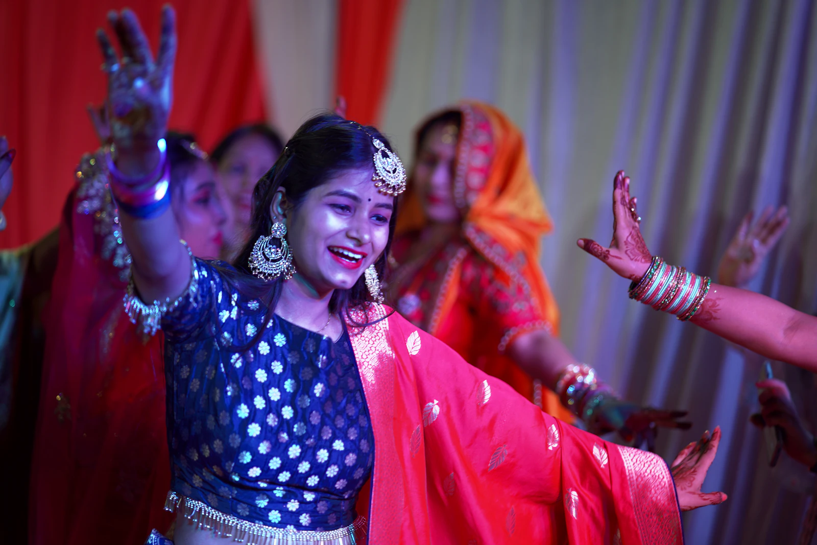 A dancer mid-spin in a blue and red outfit at a sangeet