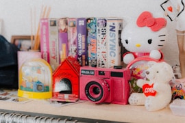 a hello kitty doll sitting on top of a table next to a camera