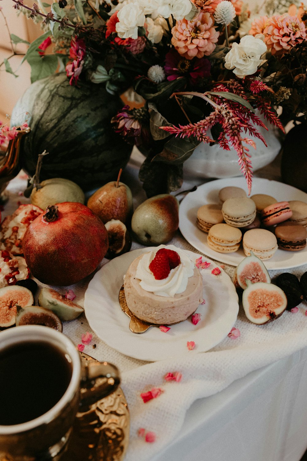 a table topped with plates of food next to a vase of flowers