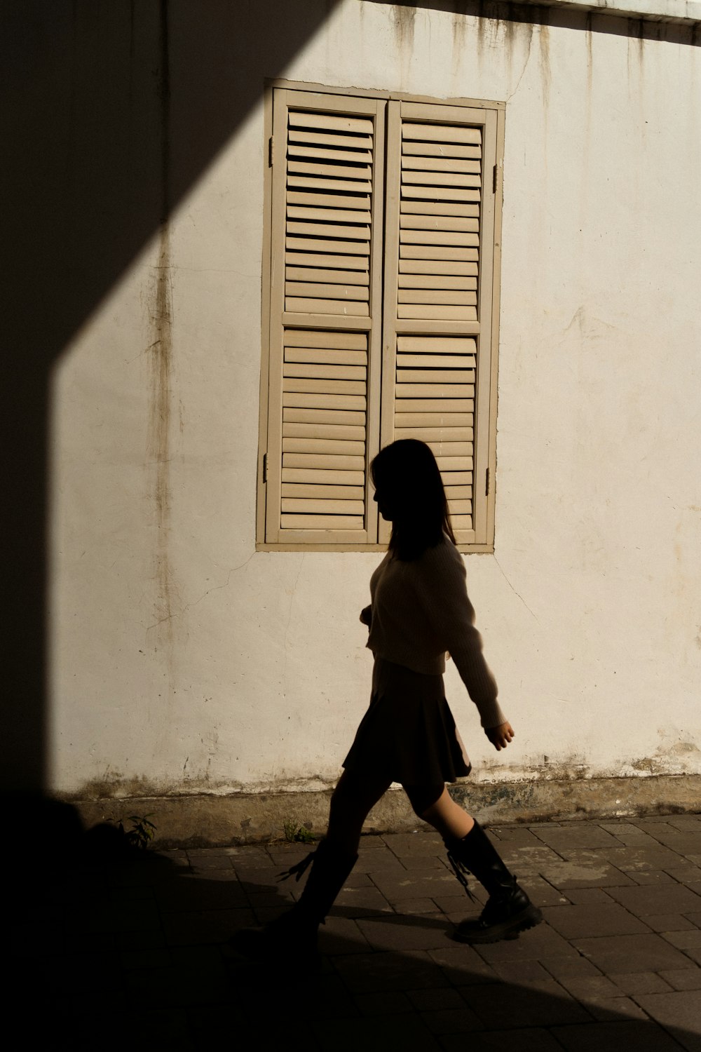 a woman walking down a street past a white building