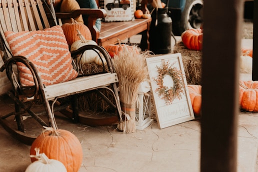 a porch with pumpkins, hay, and a rocking chair