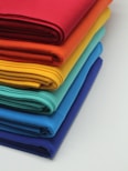 a stack of bright colored cloths on a white surface