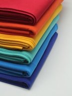 a stack of bright colored cloths on a white surface