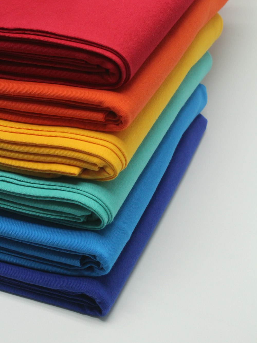 une pile de tissus de couleurs vives sur une surface blanche