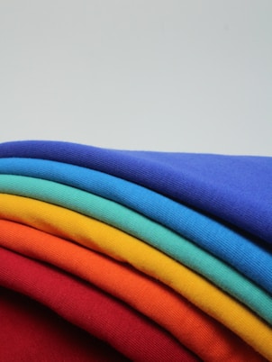 a stack of different colored t - shirts sitting on top of each other