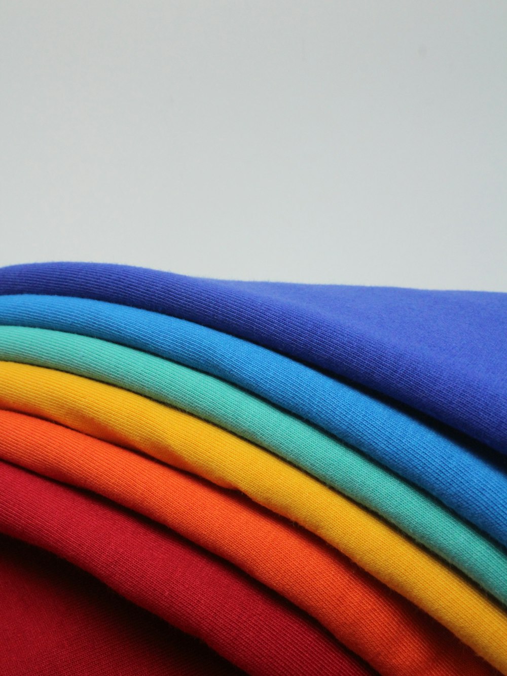 a stack of different colored t - shirts sitting on top of each other