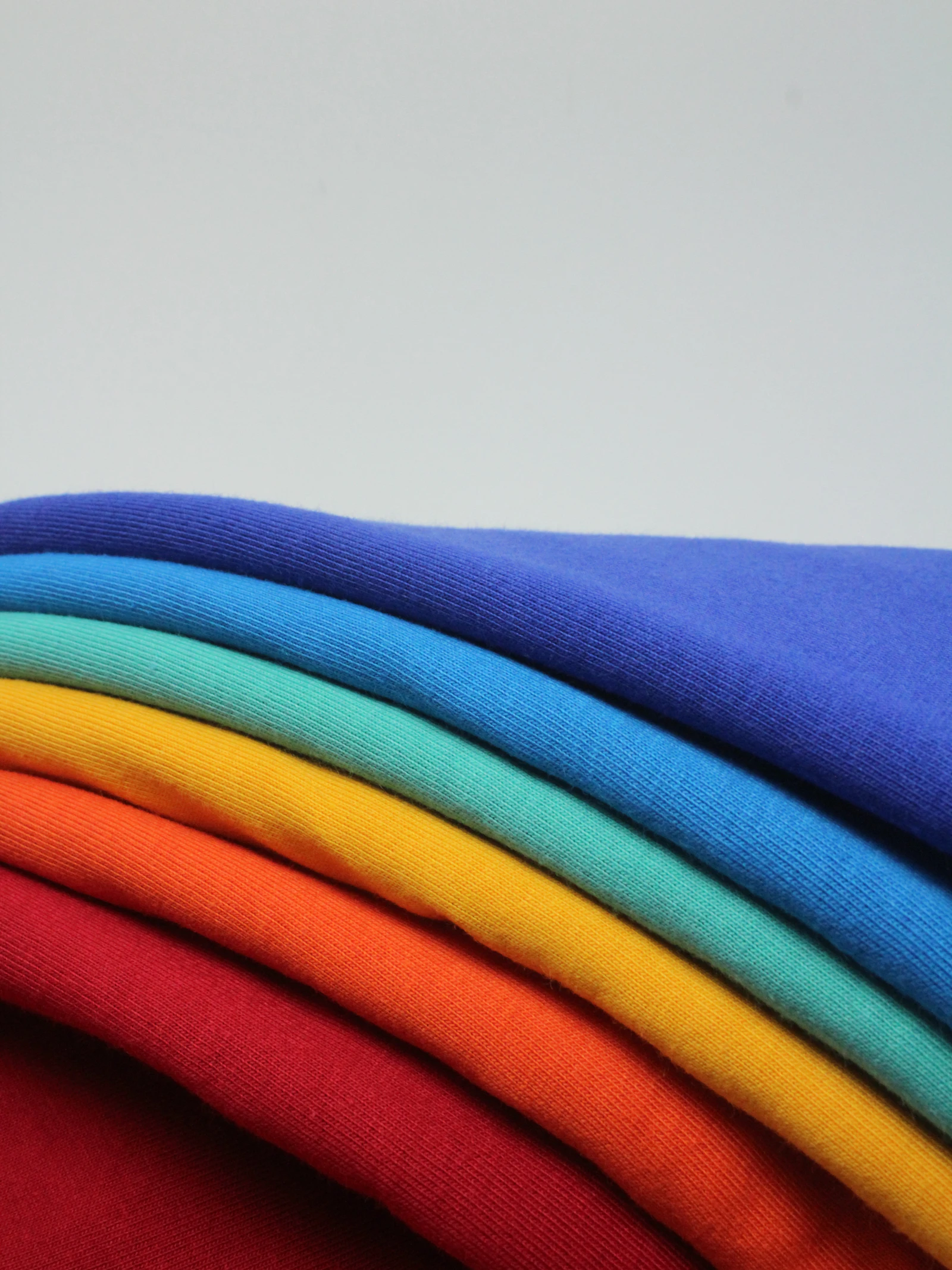 Neatly folded stacks of plain cotton jersey knit t-shirts and tanks arranged inside a garment factory
