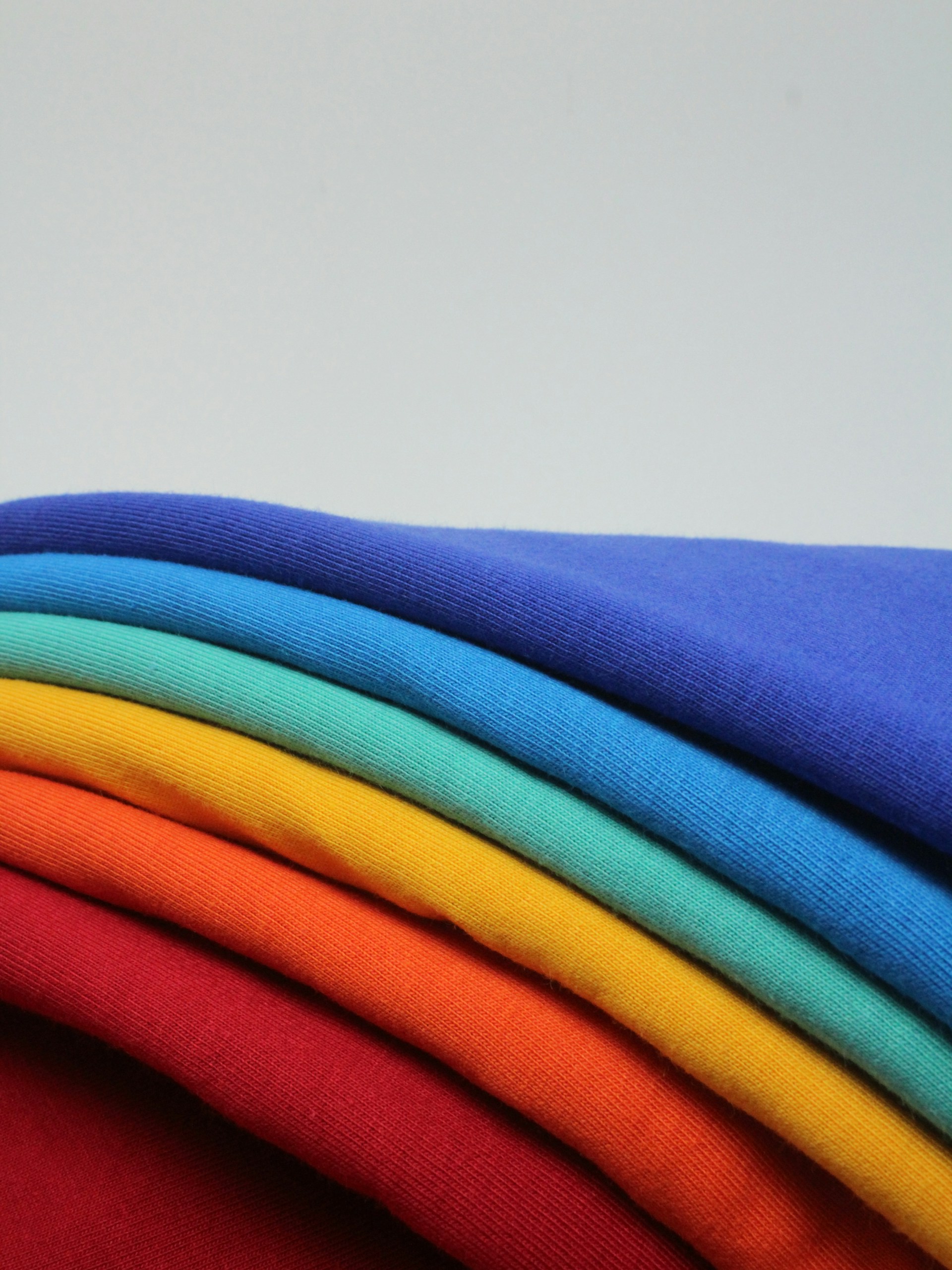 a stack of different colored t - shirts sitting on top of each other