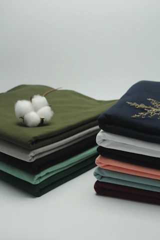 A stack of freshly laundered, crisp white hotel linens neatly folded in a bright laundry facility.