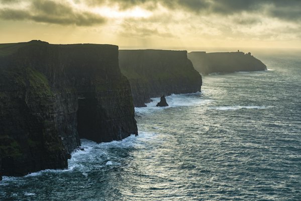 A large body of water next to a rocky cliff — Cliffs of Moher & the Burren, Ireland