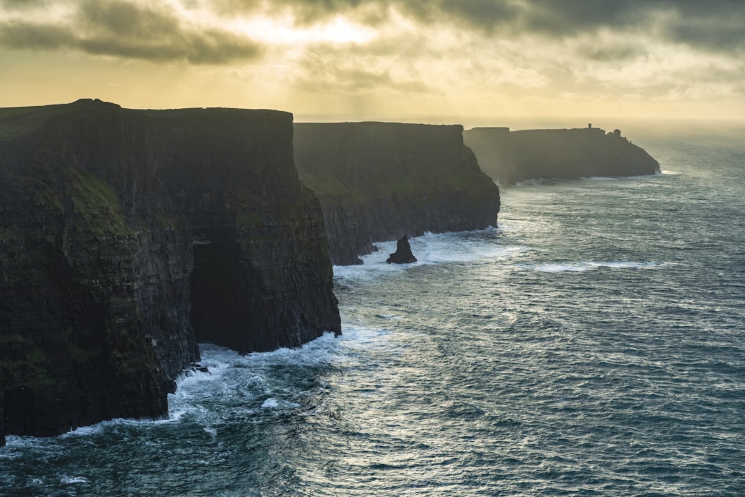 a large body of water next to a rocky cliff, Famous Cliffs of Moher in Ireland