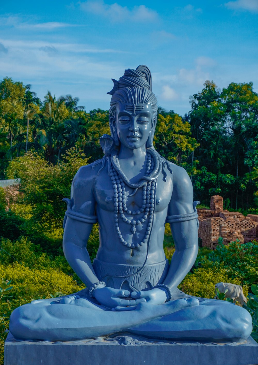 a statue of a man sitting in the middle of a forest